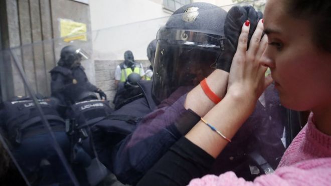 Spanish police push a girl with a shield outside a polling station in Barcelona, on October 1, 2017