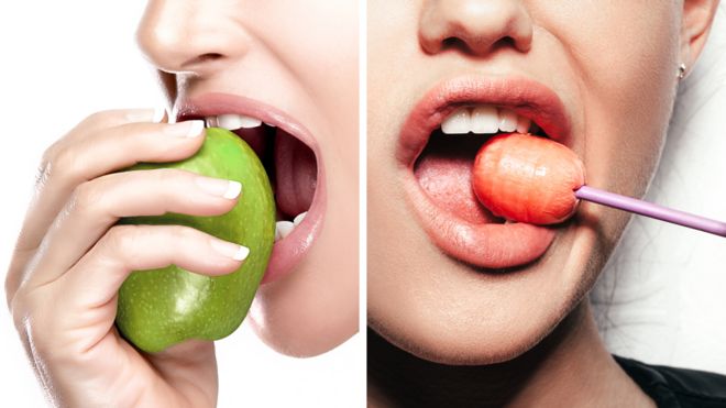 Uma mulher comendo uma maçã, outra mulher mordendo um pirulito