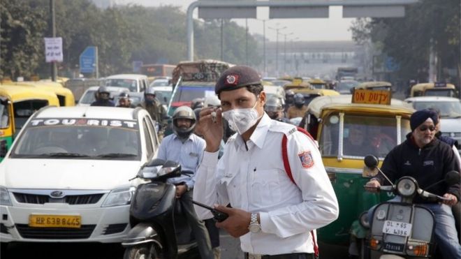 Человек ГИБДД стоит на светофоре в маске загрязнения в первый день реализации нечетной схемы для транспортных средств в Нью-Дели, Индия, 1 января 2016 года.