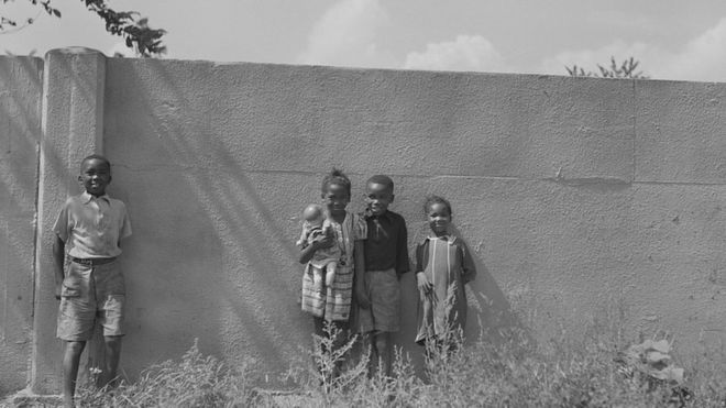Niños negros apoyados en el muro