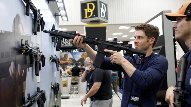 Un miembro de la NRA posa con un arma del tipo AR-15 durante la conferencia anual en Indianápolis, Indiana.
