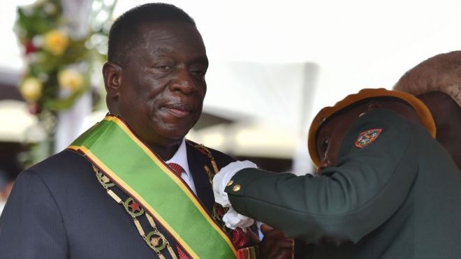 Военные офицеры прикрепляют знаки отличия на президента Эммерсона Мнангагва