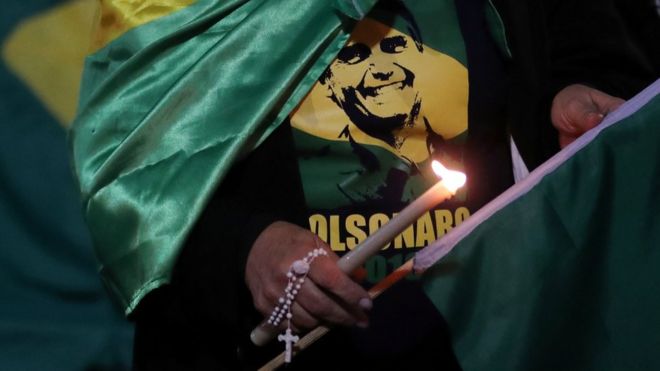 Женщина зажигает свечу для кандидата в президенты Джера Болсонаро после того, как он был ранен 6 сентября 2018 года
