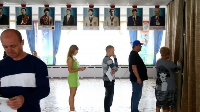 Люди стоят в очереди перед кабиной для голосования во время парламентских выборов на избирательном участке в Минске (11 сентября 2016 года)