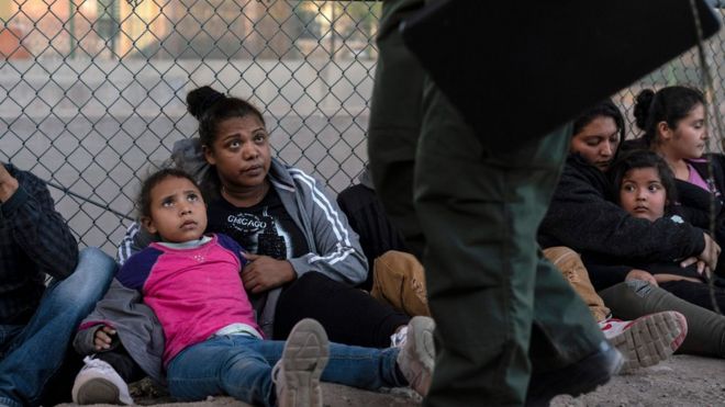 Мигранты, пойманные на границе с США, смотрят на офицеров CBP