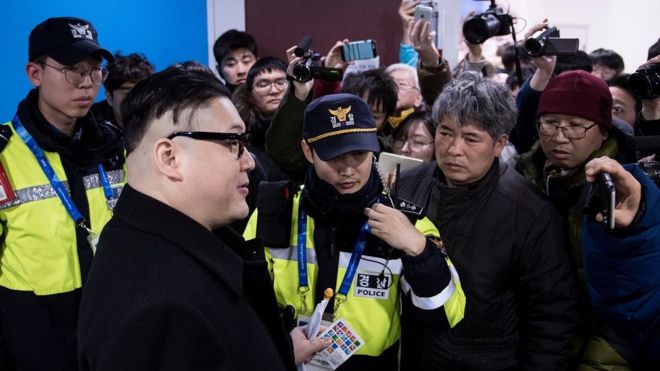 Имитатор Ким Чен Ына окружен журналистами, которые пытаются снимать его на свои камеры и телефоны