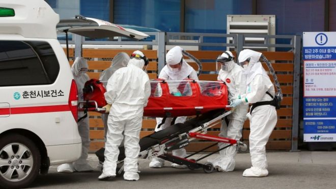 Medical workers wearing protective gear carry a patient infected with the Covid-19 coronavirus at a hospital in Chuncheon on February 22, 2020