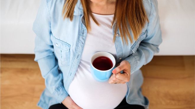Беременная женщина с чашкой