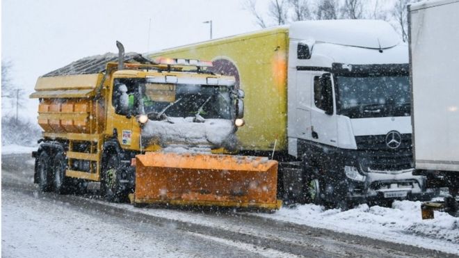 Снегоочиститель очищает снег на подъездной дороге рядом с автомагистралью M74, после того как 17 января 2018 года автомобилист провел ночь на автомагистрали в Абингтоне, Шотландия