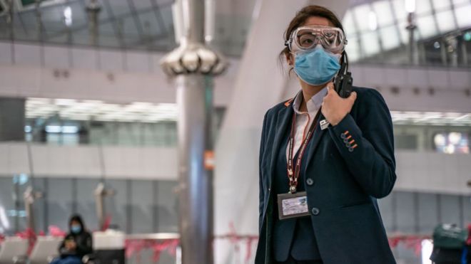 Una empleada del aeropuerto de Hong Kong usando una mascarilla.