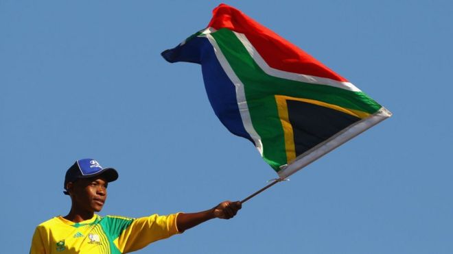 Болельщик из Южной Африки развевает свой национальный флаг перед чемпионатом мира по футболу 2010 года. Южная Африка