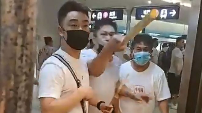 A mob of men in white T-shirts threatening pro-democracy protesters