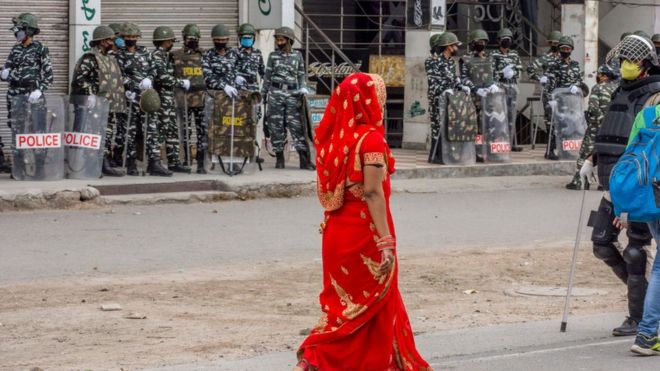 Fila de agentes de la policía y una mujer india vestida de rojo
