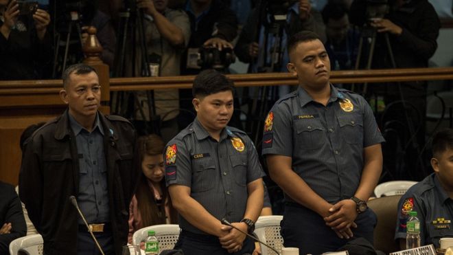 Филиппинские полицейские Арнел Оарес, Джервин Крус и Джеремиас Переда, обвиняемые в убийстве 17-летнего студента Киана Делоса Сантоса во время рейда по борьбе с наркотиками, стоят на слушаниях в Сенате в Маниле 5 сентября 2017 года.