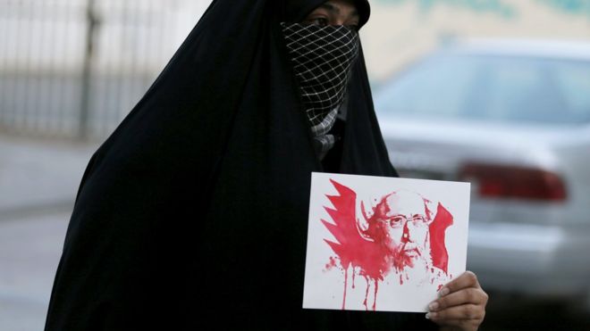 Протестующий держит изображение шейха Нимра в бахрейнской деревне Санабис