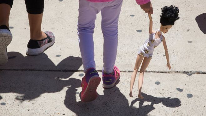Una niña hondureña lleva en la mano una muñeca mientras camina con su madre, ambas inmigrantes, en McAllen, Texas. el 17 de junio.