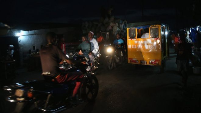 Люди едут в темноте в трущобах Вест-Пойнт, где в нескольких домах есть электричество, 15 августа 2014 года в Монровии, Либерия