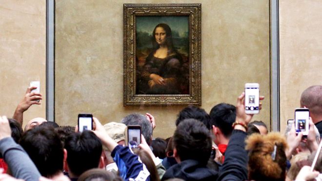 Tourists look at the Mona Lisa painting in the Louvre museum