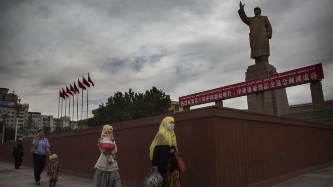 Мусульманки проходят мимо статуи Мао Цзэдуна в Кашгаре, Синьцзян (июль 2014 г.)