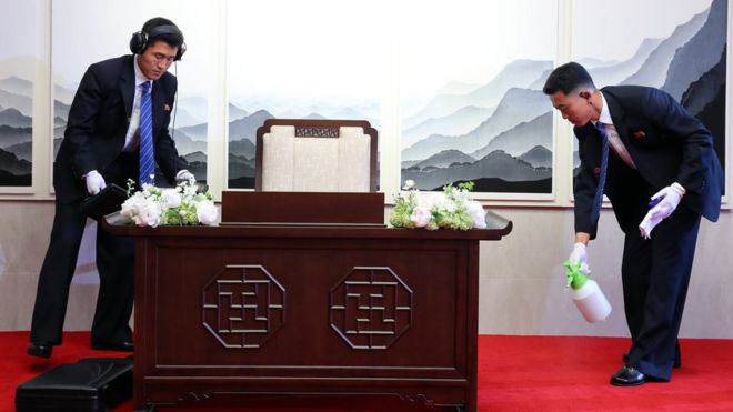 Des agents nord coréens désinfectent le fauteuil et le bureau sur lequel le leader nord-coréen va s'assoeir pour signer un livre d'or