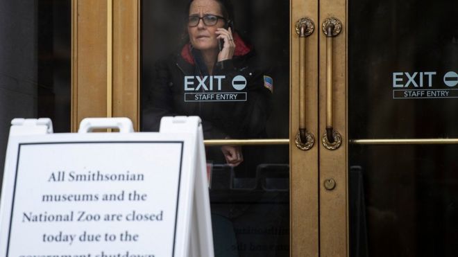 Сотрудница правительства США разговаривает по телефону, когда она выходит из закрытого Смитсоновского музея в Вашингтоне 18 января 2019 года.