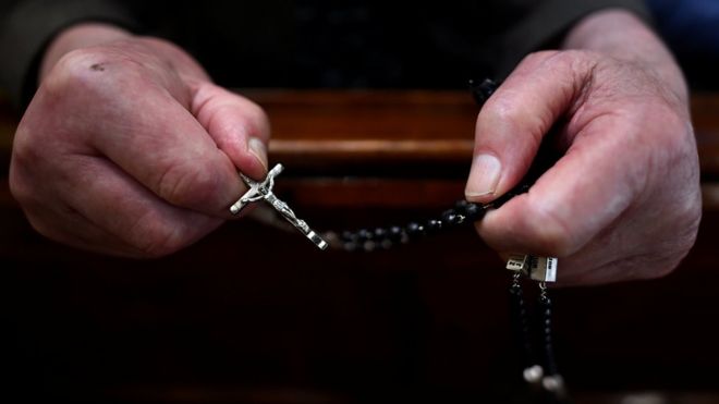 Видны руки верующего, держащего четки в церкви в Мукно, Ирландия (20 июня 2017 года)