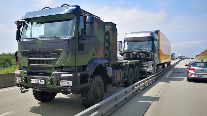Военный автомобиль показан перед грузовиком без водителя