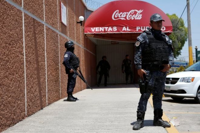 Полицейские охраняют вход в распределительный завод Coca-Cola FEMSA после его закрытия из-за проблем безопасности и насилия во время предвыборной акции Независимого кандидата в президенты Маргариты Завала (невидимой) в Сьюдад-Альтамирано, штат Герреро, Мексика, 3 апреля 2018 года. .