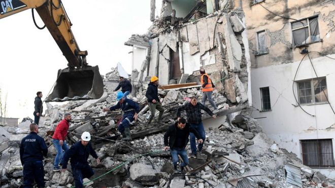 Emergency workers clear debris at a damaged building in Thumane