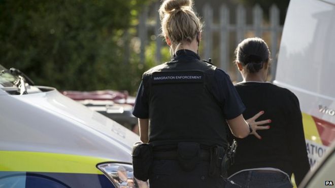 Сотрудники иммиграционной службы арестовывают женщину во время рейда в Слау, Беркшир.