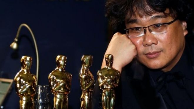 O diretor Bong Joon Ho ao lado de estatuetas do Oscar