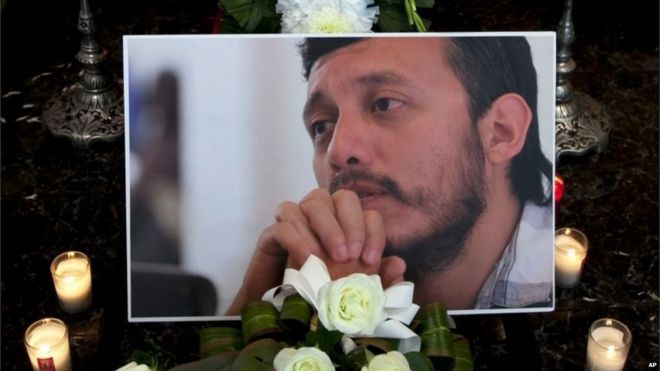 Фотография убитого фотожурналиста Рубена Эспиноса сидит среди цветов и свечей перед его гробом в похоронном бюро до его пробуждения в Мехико, понедельник, 3 августа 2015 года.