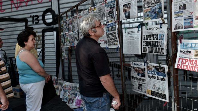 Люди читают заголовки газет в Афинах, 13 июля 2015 года