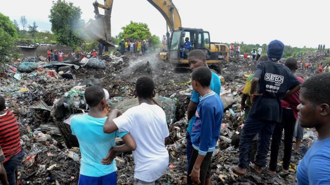 Люди наблюдают за тем, как спасатели ищут тела погибших, захороненных под обрушившимися кучами мусора в Мапуту, Мозамбик, 19 февраля 2018 года