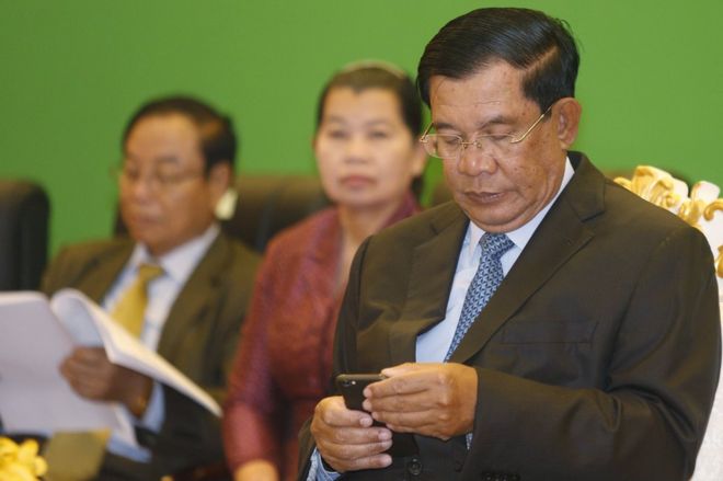 Премьер-министр Камбоджи Хун Сен проверяет свой телефон