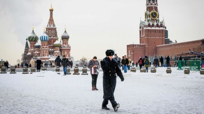 A serviceman walks in front of St Basil's Cathedral and the Kremlin