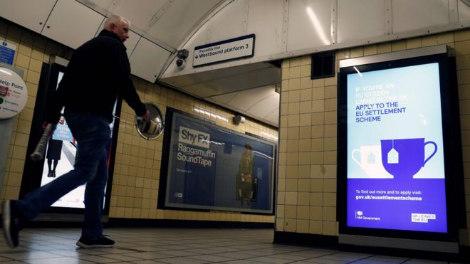 Мужчина проходит мимо плаката, призывающего граждан ЕС обратиться к британской схеме урегулирования после Брексита