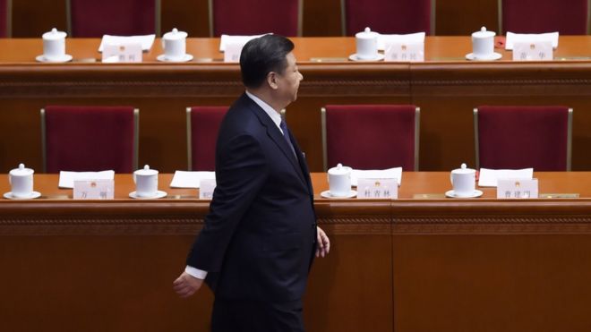 Xi Jinping walking in front of delegates' tables and empty chairs
