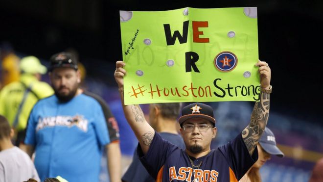 Поклонник Хьюстон Астрос держит знак для тех, кто пострадал от урагана Харви