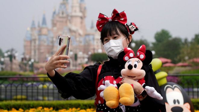 Посетитель, одетый как персонаж Диснея, делает селфи в защитной маске в шанхайском Диснейленде, когда тематический парк Шанхайского Диснейленда открывается после закрытия из-за вспышки коронавирусной болезни (COVID-19) в