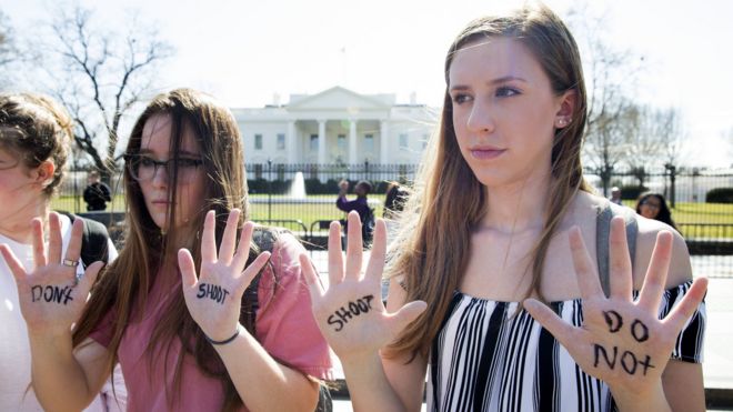 young protesters show their palms, with don't shoot written on them