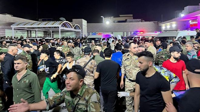 Soldiers and emergency responders gather around ambulances carrying wounded people after a fire broke out at a wedding in Iraq
