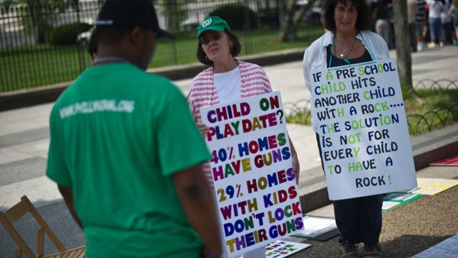 Люди, призывающие к ужесточению законов об оружии, держат знаки во время их еженедельной акции протеста перед Белым домом в Вашингтоне 17 июня 2013 года.