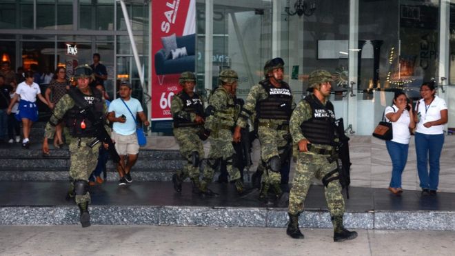 Мексиканские солдаты эвакуируют мирных жителей из торгового центра в непосредственной близости от места, где разразилась стрельба в результате нападения на здание государственного обвинения Кинтана-Роо в Канкуне, Мексика