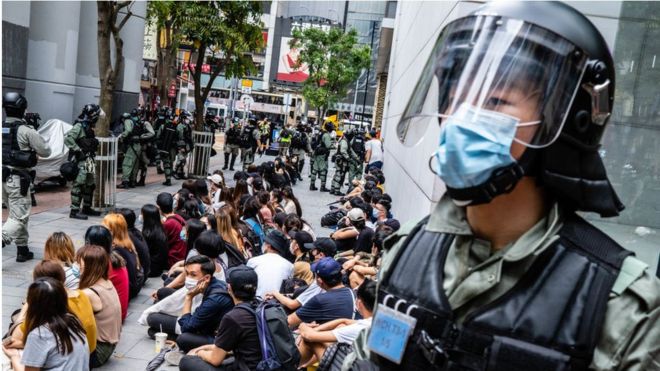 ОМОН задерживает группу протестующих во время демонстрации в Гонконге.