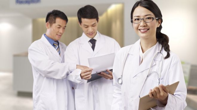 Женщина-врач из Китая и двое врачей-мужчин на заднем плане