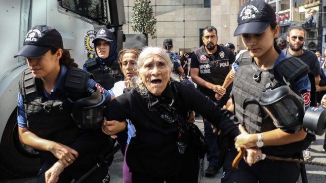 An elderly female demonstrator is detained by police