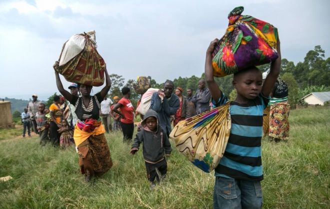 Конголезцы несут свои вещи после того, как 24 января 2018 года они пересекли границу с Демократической Республикой Конго и стали беженцами в деревне Нтеко на западе Уганды.
