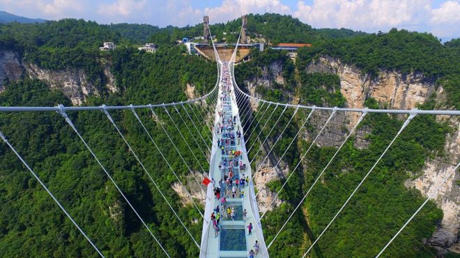 Foto area mostra dezenas de turistas em ponte de vidro de Zhangjiajie