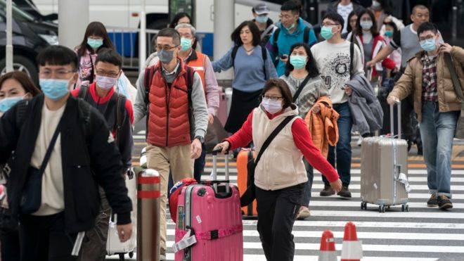Группа китайских туристов идет у вестибюля прилета в аэропорту Нарита 24 января 2020 года в Нарите, Япония.